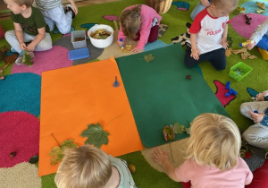 Dzieci przyklejają na karton kolorowe liście