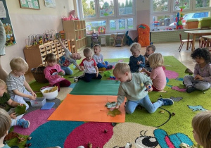 Dzieci układają na kartonie kompozycje z liści i kasztanów