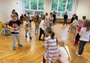 Dzieci chodzą po sali z kulkami z gazety