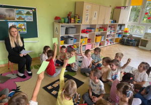 Dzieci podnoszą rękę z kartką zieloną, gdy psycholog zadaje pytanie