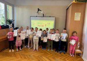 Dzieci pozują do zdjęcia z dyplomami i nagrodami