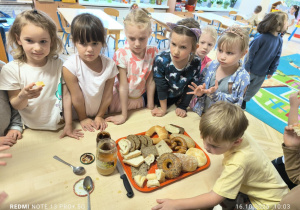 Dzieci stoją przy stole i oglądają różne rodzaje pieczywa