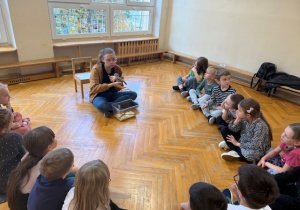 Dzieci siedzą w kole na podłodze i słuchają o życiu lotopałanki