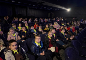 Dzieci siedzą w fotelach czekając na przedstawienie teatralne