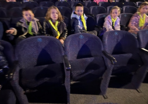 Dzieci siedzą w fotelach czekając na przedstawienie teatralne