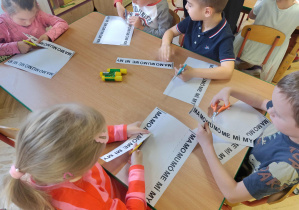 Dzieci wycinają pasek z sylabami i układają sylabę do sylaby