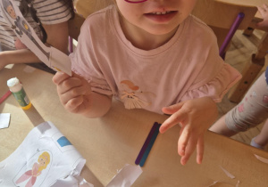 Dziewczynka wycina sylwetę postaci z papieru