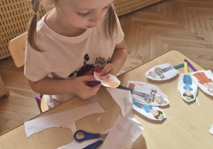 Dziewczynka wycina sylwetę postaci z papieru
