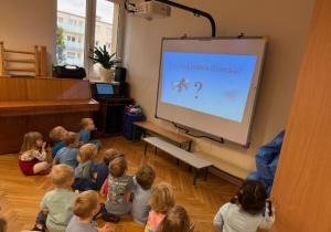 Dzieci siedzą i oglądają film edukacyjny "Prawa dziecka"