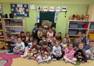 Dzieci siedzą na dywanie z swoimi misiami