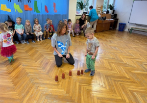 zabawa - Chłopiec szuka kubeczka w którym ukryty jest kamień