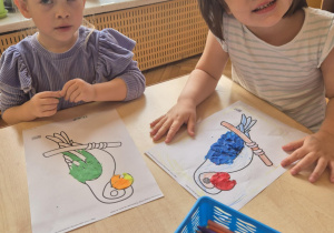 Dziewczynki wyklejają papugę plasteliną