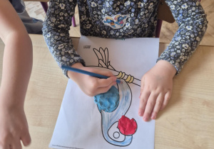 Dziewczynka koloruje sylwetę papugi