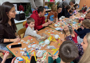 Rodzice wspólnie z dziećmi wykonują dekoracje na choinkę klasową