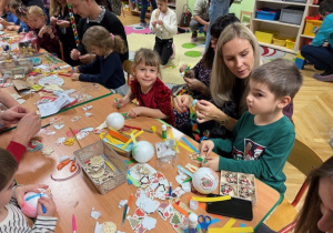 Rodzice wspólnie z dziećmi wykonują kolorowe dekoracje na choinkę klasową