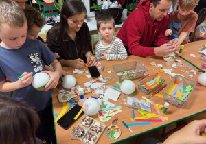 Rodzice wspólnie z dziećmi wykonują dekoracje na choinkę klasową