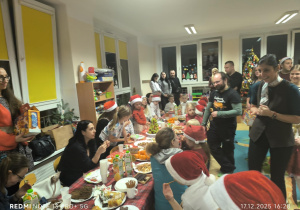 Dzieci i Rodzice siedzą przy stole i jedzą potrawy wigilijne