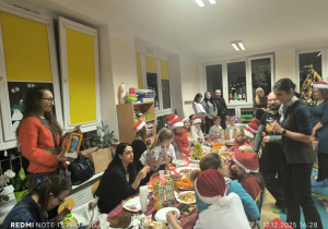 Dzieci i Rodzice siedzą przy stole i jedzą potrawy wigilijne