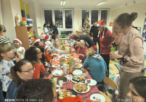 Dzieci i Rodzice siedzą przy stole i jedzą potrawy wigilijne