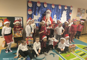 Dzieci stoją wspólnie z Mikołajem i pozują do zdjęcia