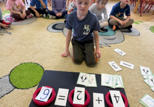 Chłopiec układa pingwiny do danej liczby