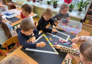 Chłopiec i dziewczynka układa rytmy z klocków do szablonu na kartonie