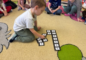 Chłopiec układa paradygmat z sylabami "ba, bo, bu, bó,be, bi,by"