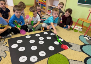 Chłopiec dotyka łapką sylabę i przelicza ilość sylab