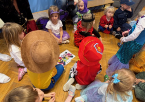 Dzieci siedzą na podłodze i składają obrazek pocięty z kilku części