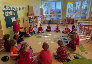 Dzieci siedzą na dywanie i będą losować imię swojej przyjaciółki lub przyjaciela