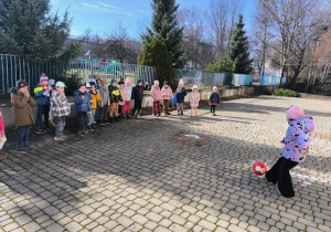 Dziewczynka kopie piłkę w ogrodzie