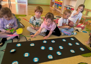 Dziewczynka wskazuje takie same sylaby na kartonie