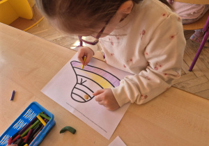 Dziewczynka koloruje kredkami kapelusz pani Wiosny