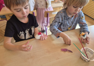 Chłopcy przyklejają materiały i piórka