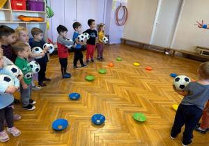 Dzieci stoją z piłką przed talerzykiem plastikowym